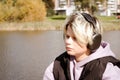 Portrait of sad caucasian teenager boy sitting on the lake shore and listening to music on wireless headphones Royalty Free Stock Photo