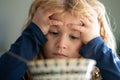 Portrait of sad child having breakfast at home. Portrait of sweet little kid boy with blonde hair eating soup from plate Royalty Free Stock Photo