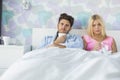 Portrait of sad couple holding coffee mug and glass while relaxing on bed Royalty Free Stock Photo