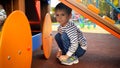 Portrait of sad crying boy sitting under slide on children playground at park Royalty Free Stock Photo