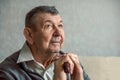 Portrait of sad elderly man on grey background. Thoughtful look of old senior sitting alone at home. Close-up of Royalty Free Stock Photo