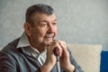 Portrait of sad elderly man on grey background. Thoughtful look of old senior sitting alone at home. Close-up of Royalty Free Stock Photo