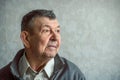 Portrait of sad elderly man on grey background. Thoughtful look of old senior sitting alone at home. Close-up of Royalty Free Stock Photo