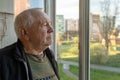 Portrait of a sad elderly man looking out the window at home. Lonely elderly man looking out the window Royalty Free Stock Photo