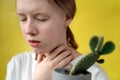 portrait of a sad girl with a cactus on a yellow background. Teen girl with problem. Blonde female is holding on to the Royalty Free Stock Photo