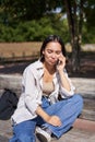 Portrait of sad girl talking on mobile phone and sulking. Young woman having an uneasy conversation on telephone Royalty Free Stock Photo