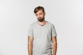 Portrait of sad and gloomy bearded man in gray t-shirt, frowning and looking miserable, standing over white background Royalty Free Stock Photo