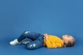 Portrait of sad little girl sitting on blue studio background, autism concept