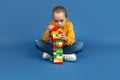 Portrait of sad little girl sitting on blue studio background, autism concept