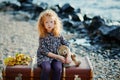 Portrait of a sad little girl. Sitting on an old suitcase with h Royalty Free Stock Photo