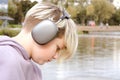 Portrait of sad lonely teenager boy sitting on the lake shore and listening to music on wireless headphones Royalty Free Stock Photo