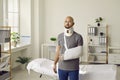 Portrait of sad man with neck brace and sling on his arm who was injured after car accident.