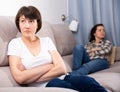 Mature female sitting at sofa after quarrel quarrel, woman on background