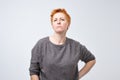 Portrait of a sad middle-aged woman with short red hair on a gray background. Royalty Free Stock Photo