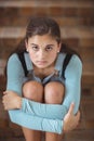 Portrait of sad schoolgirl sitting alone on staircase