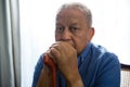 Portrait of sad senior man holding walking cane while sitting on chair Royalty Free Stock Photo