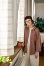 Portrait of sad teenage girl standing by window at home Royalty Free Stock Photo