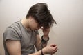 Portrait of a sad teenager in handcuffs on a gray background, medium plan. Juvenile delinquent, criminal liability of minors. Royalty Free Stock Photo