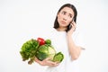 Portrait of sad, unhappy young woman, making phone call, talking with someone and holding vegetables, white background Royalty Free Stock Photo