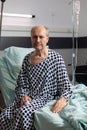 Portrait of sad, unwell senior man sitting on the edge of hospital bed Royalty Free Stock Photo