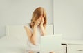 Portrait of sad upset crying young woman working with laptop on the bed in white room at home Royalty Free Stock Photo