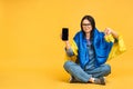 Portrait of sad woman holding in hands Ukrainian flag isolated over yellow background. Sitting on the floor in lotus pose. Using Royalty Free Stock Photo