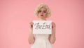 Portrait of sad woman holding a poster with the inscription of the end. Woman in the look of Marilyn Monroe in studio on Royalty Free Stock Photo