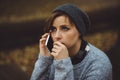 Portrait of sad woman sitting alone in the forest with smartphone. Solitude concept. Millenial dealing with problems and Royalty Free Stock Photo