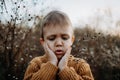 Portrait of sad, worried little boy wearing knitted sweater in nautre, autumn concept. Royalty Free Stock Photo