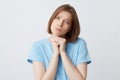 Portrait of sad worried young woman in blue t shirt folded hands under her chin and feels sorry isolated over white background Royalty Free Stock Photo