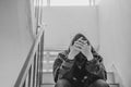 Portrait of sad young man covering his face with hands sitting on old stairs. Royalty Free Stock Photo