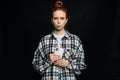 Portrait of sad young woman holding mobile phone and looking at camera on isolated black background. Royalty Free Stock Photo