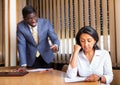 Saddened businesswoman sitting in office with dissatisfied male colleague