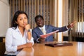 Saddened businesswoman sitting in office with dissatisfied male colleague