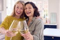Portrait Of Same Sex Mature Female Couple Celebrating With Glass Of Wine At Home Together