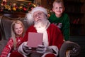 Portrait Santa Claus and children. Blonde girl and boy opening Christmas gift near Christmas tree.Brother and sister