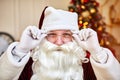 Portrait of Santa Claus with glasses near the fireplace and christmas tree with gifts. New year and Merry Christmas , happy Royalty Free Stock Photo