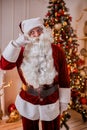 Portrait of Santa Claus with glasses near the fireplace and christmas tree with gifts. New year and Merry Christmas , happy Royalty Free Stock Photo