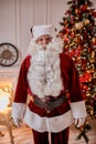 Portrait of Santa Claus with glasses near the fireplace and christmas tree with gifts. New year and Merry Christmas , happy Royalty Free Stock Photo