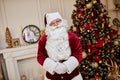 Portrait of Santa Claus with glasses near the fireplace and christmas tree with gifts. New year and Merry Christmas , happy Royalty Free Stock Photo