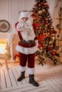 Portrait of Santa Claus with glasses near the fireplace and christmas tree with gifts. New year and Merry Christmas , happy Royalty Free Stock Photo