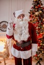 Portrait of Santa Claus with glasses near the fireplace and christmas tree with gifts. New year and Merry Christmas , happy Royalty Free Stock Photo