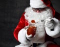 Portrait of Santa Claus holding spoonful and a jar of red caviar fish salmon on dark gray. New year and Merry Christmas