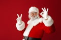 Portrait of Santa Claus showing OK and victory gesture on color background Royalty Free Stock Photo