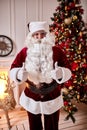 Portrait of Santa Claus showing thumb up near the fireplace and christmas tree with gifts. New year and Merry Christmas , happy Royalty Free Stock Photo