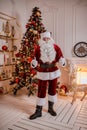 Portrait of Santa Claus showing thumb up near the fireplace and christmas tree with gifts. New year and Merry Christmas , happy Royalty Free Stock Photo