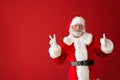 Portrait of Santa Claus showing thumb-up and victory gesture on color background Royalty Free Stock Photo