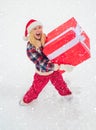 Woman in snow. Portrait of Santa woman with huge red gift looking at camera. Christmas Woman holding a huge gift box Royalty Free Stock Photo