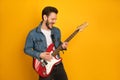 A portrait of sassy handsome man playing electric guitar, smiling pleased