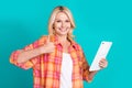 Portrait of satified woman with straight hair dressed plaid shirt holding tablet show thumb up isolated on turquoise